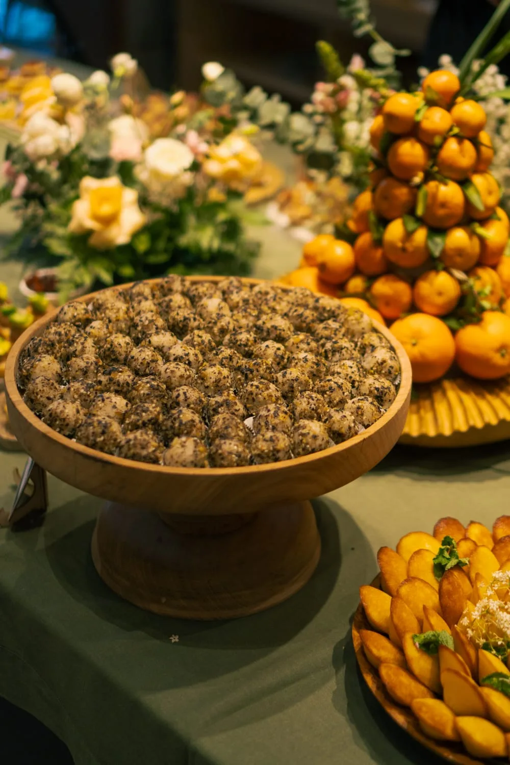 Herb-rolled truffle balls on a grazing table with a clementine tower and fresh florals