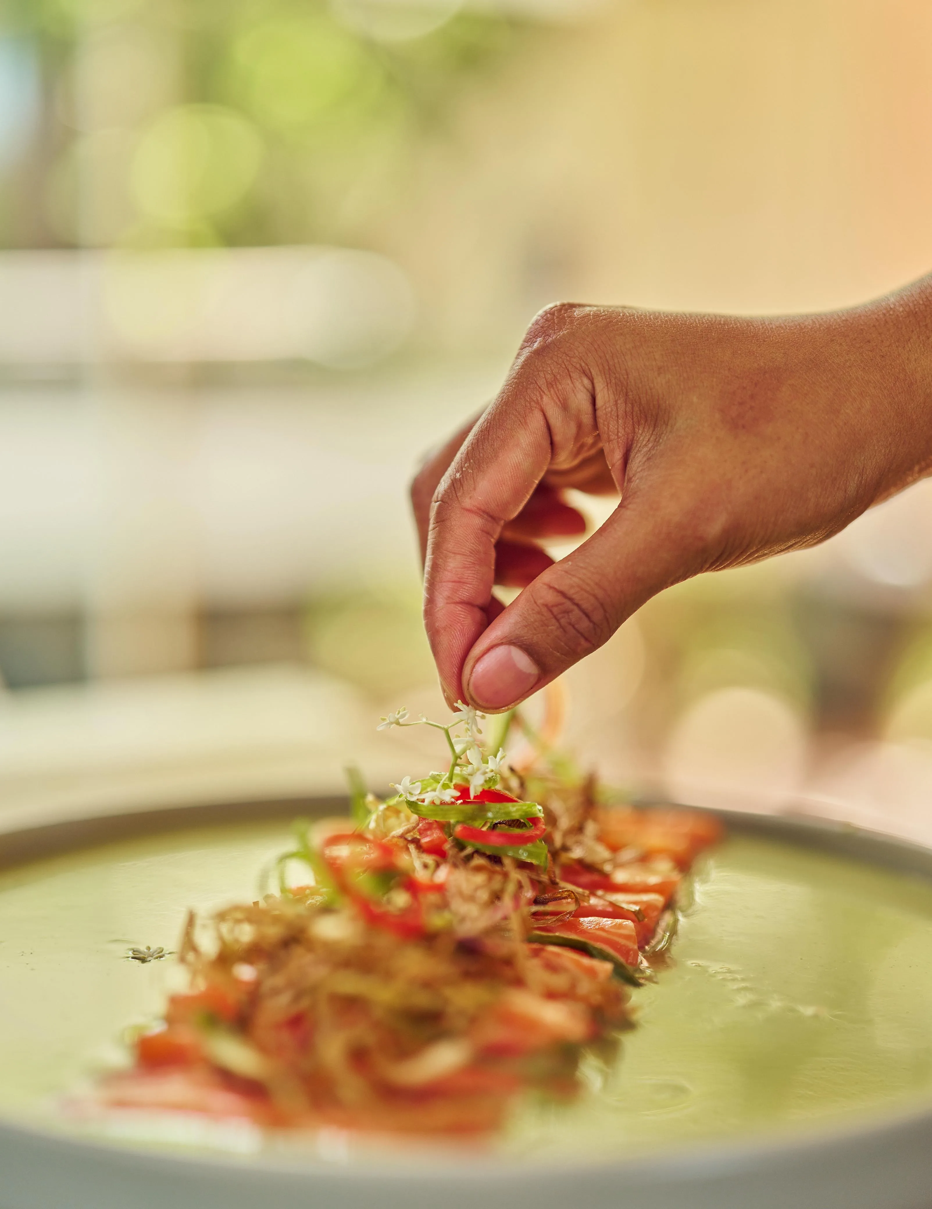 Plating tomato salad by hand with edible flower